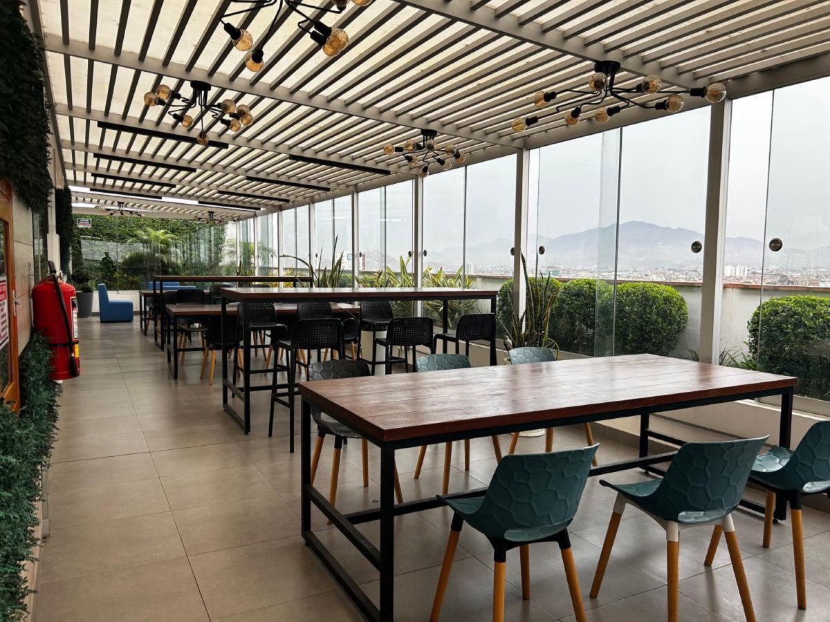 Terraza social techada con mesas y vista a la ciudad en MODO